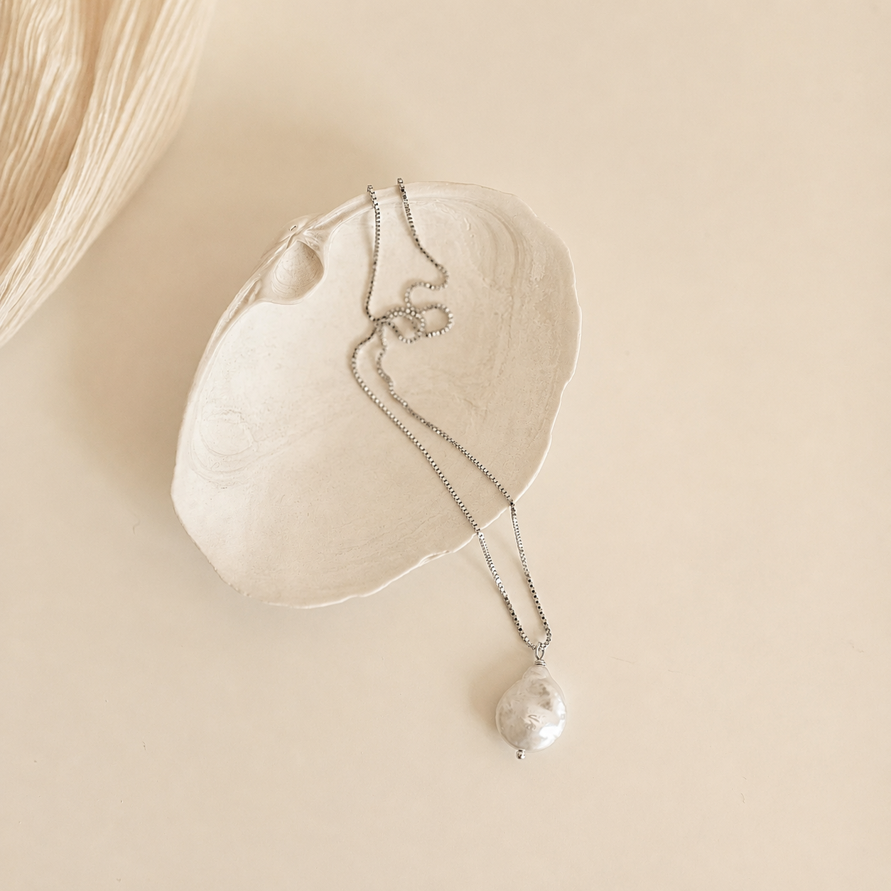 Pearl necklace on a white shell with a beige background